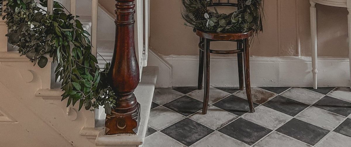 Dark wooden chair with woven greenery wreath on seat showcasing hallway tile ideas for a grand entrance