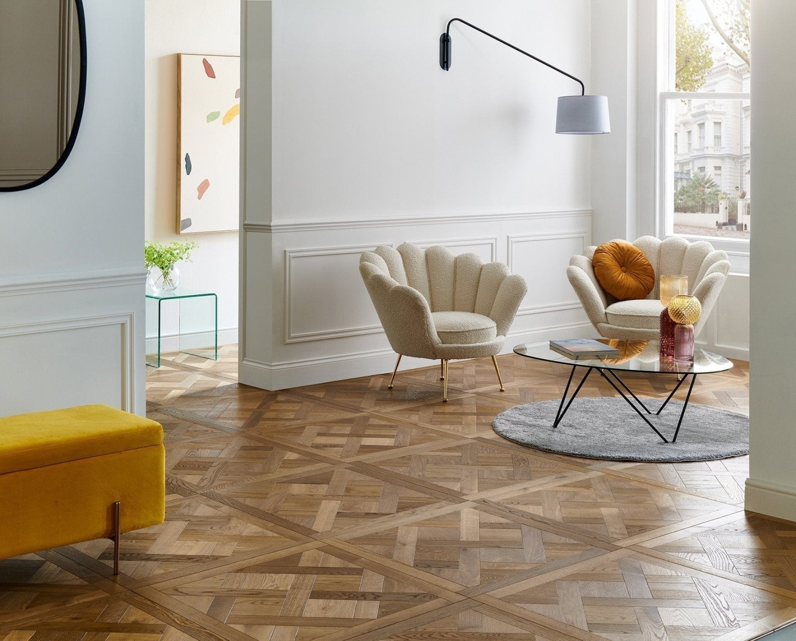 Cream-colored shell-shaped armchairs with gold-tone legs complementing parquet flooring in a stylish living space
