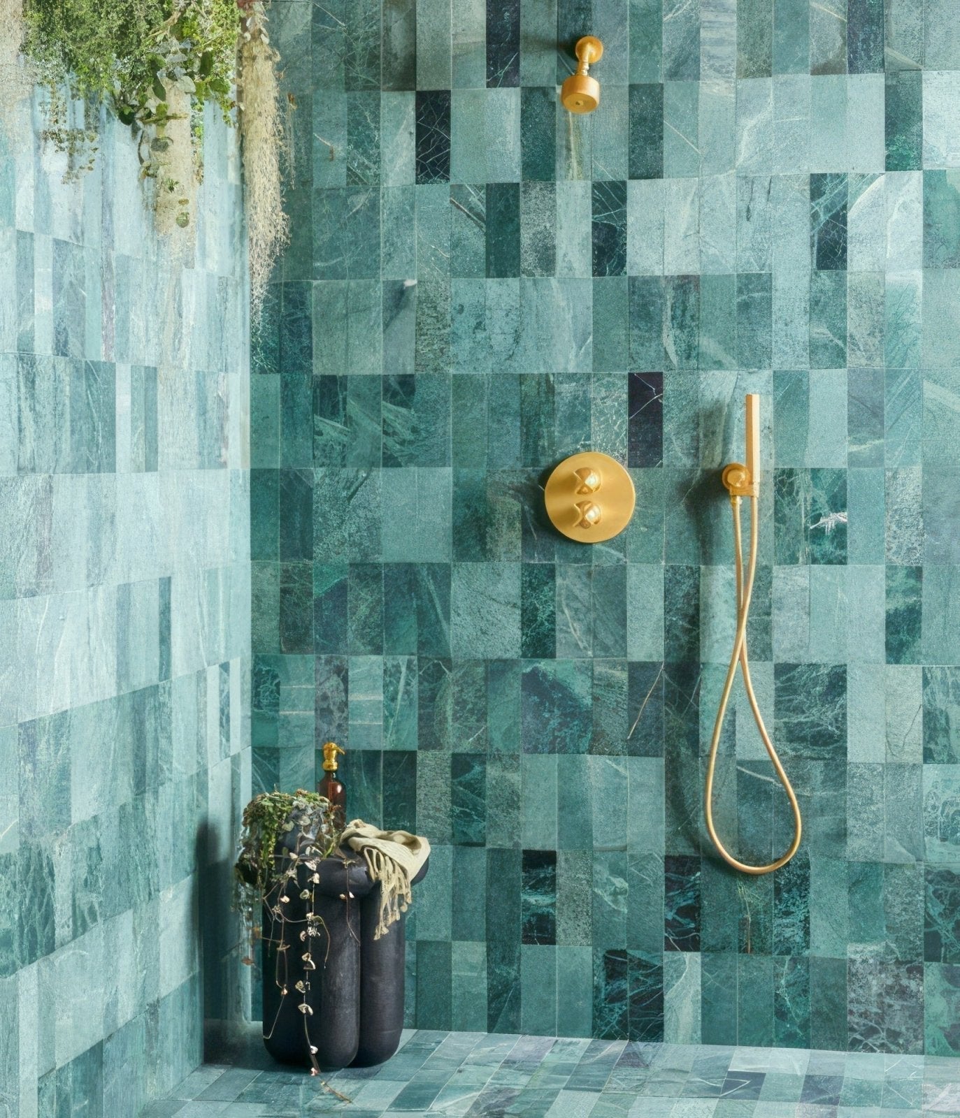 Gold-toned shower fixture with teal and green marble tiles in a wet room design to transform your home