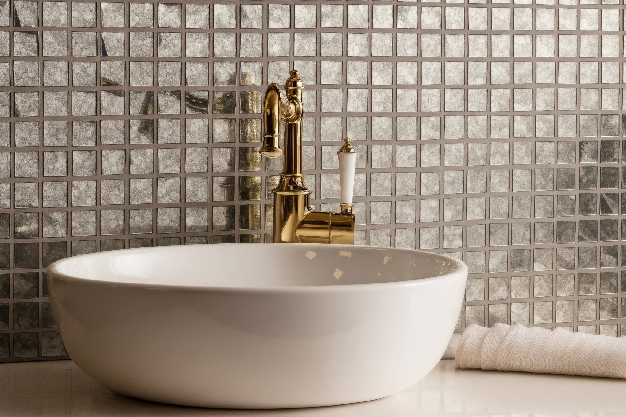 White ceramic vessel sink with polished gold faucet displayed with glass mosaic tiles background