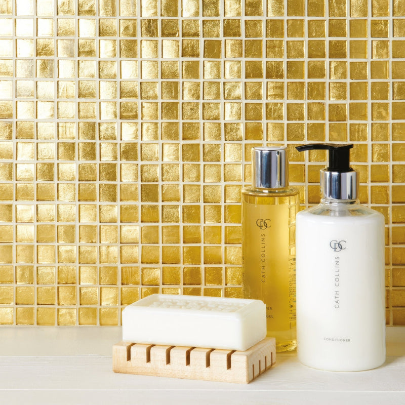 White bar of soap resting on a light wood soap dish in a gold tiles collection display
