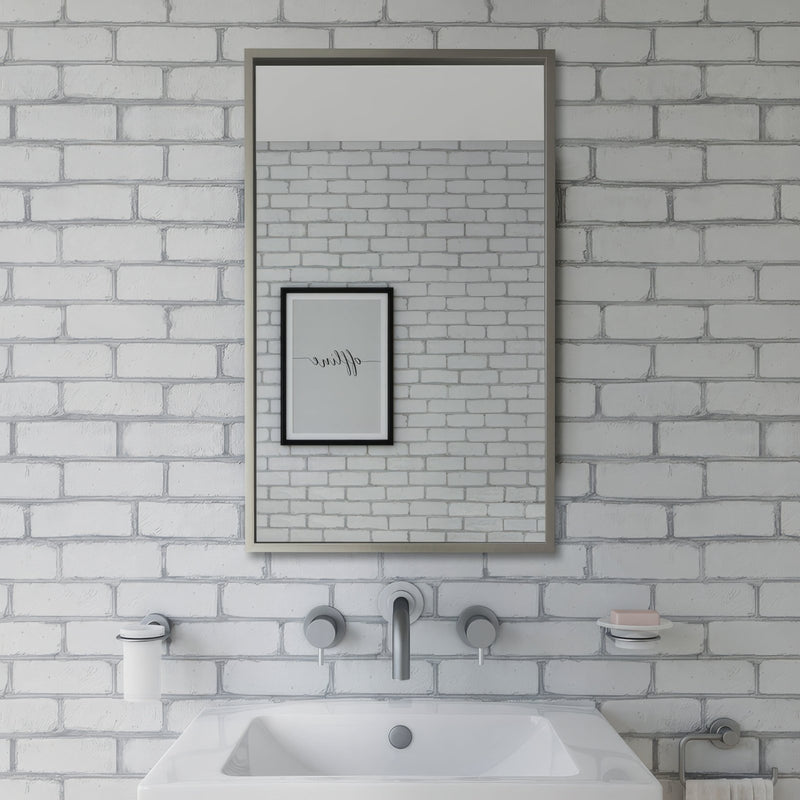 Rectangular mirror with sleek metallic frame mounted above white sink on whitewashed brick wall in rectangular mirrors collection