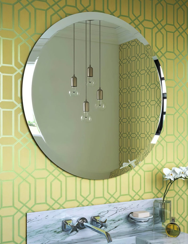Round frameless mirror with sleek chrome border mounted above a marble countertop in round mirrors collection.