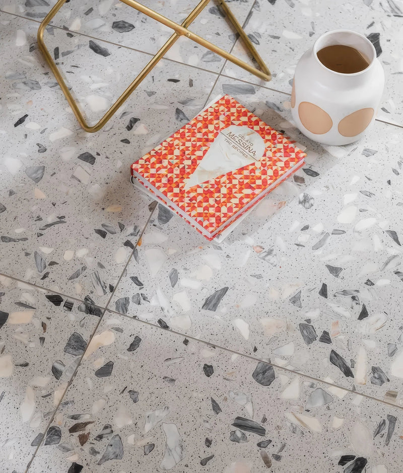 A vibrant orange and white geometric patterned glossy book featuring the messa brand from the terrazzo tiles collection