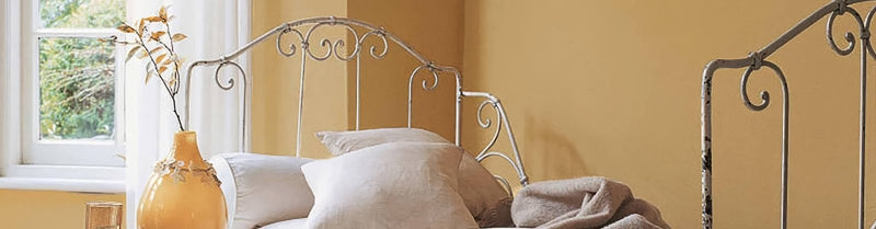 Ornate white wrought iron bed frame with curved scrollwork design from yellow paint and orange paint collection