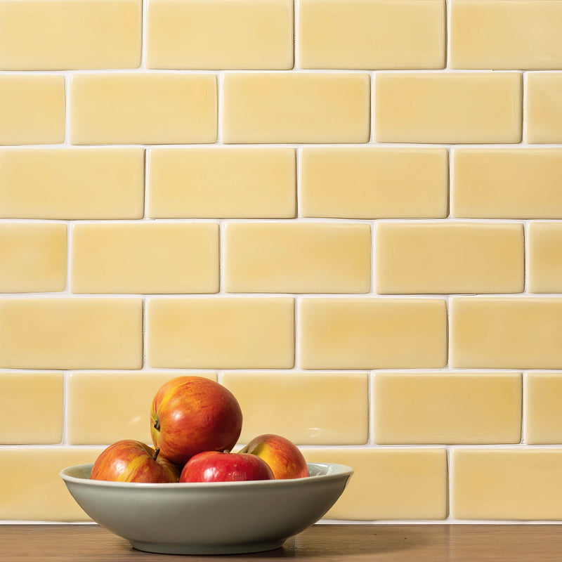 A light gray ceramic bowl filled with red and yellow apples from the yellow tiles collection