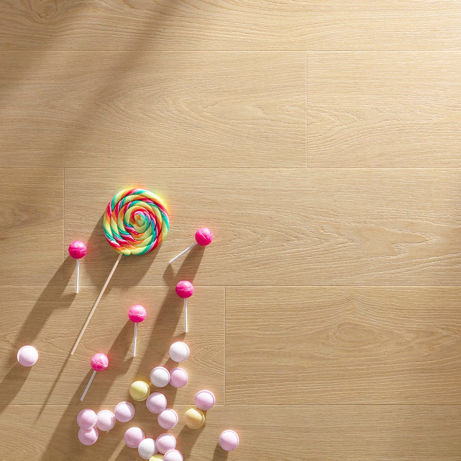 Paris tan f001 long vinyl planks on light wood flooring with a vibrant rainbow swirl lollipop and pink white candies