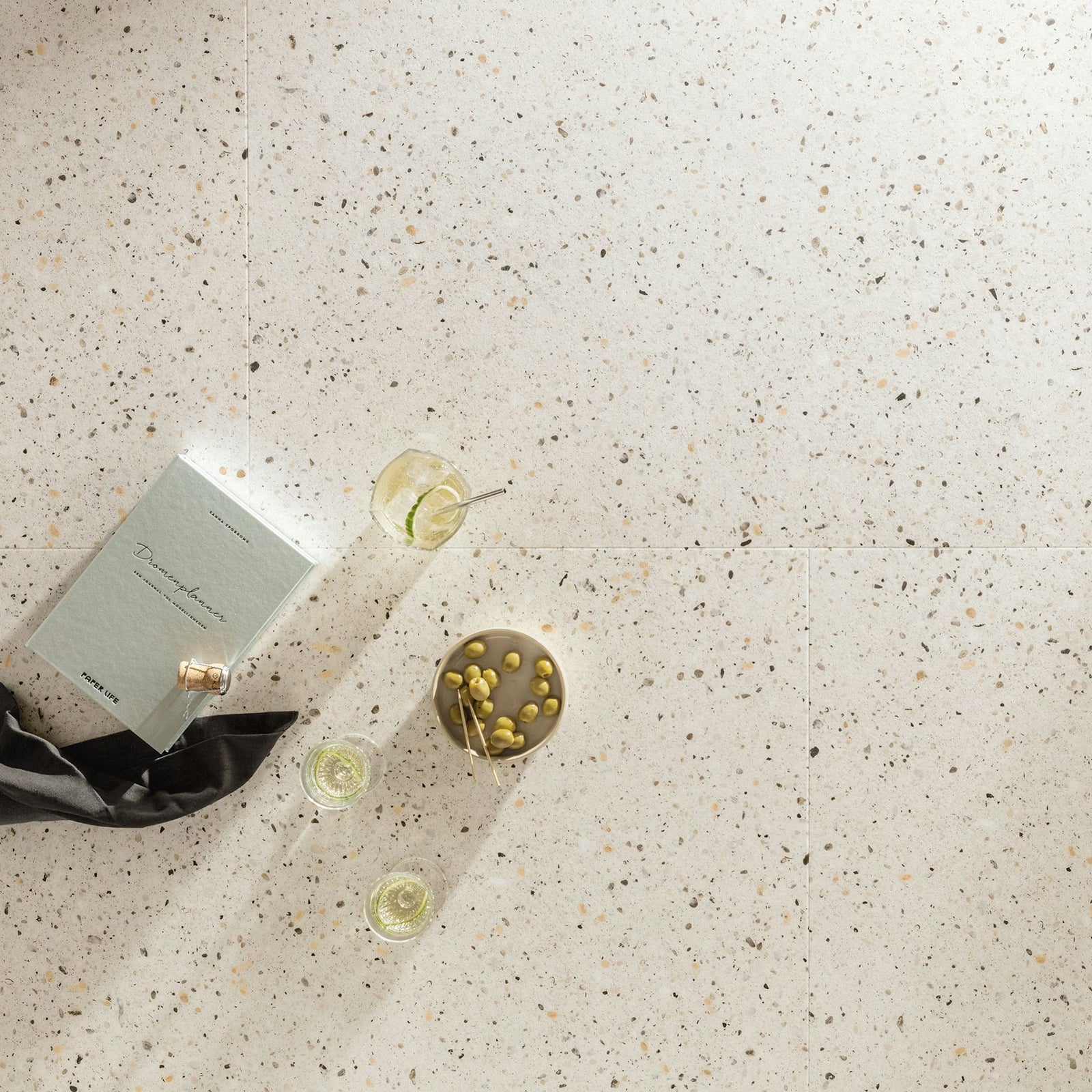 Piccolo f032 terrazzo big vinyl tiles featuring a light gray terrazzo floor with black beige and brown flecks pattern