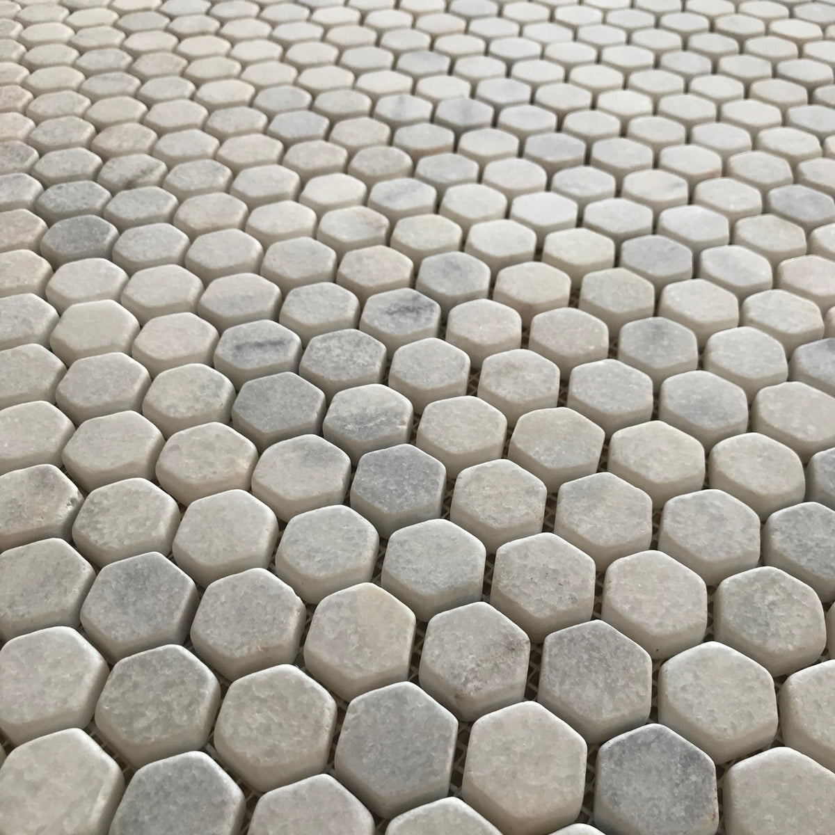 Full sheet of Carrara white hexagon mosaic viewed square on, showing veining variation between pieces