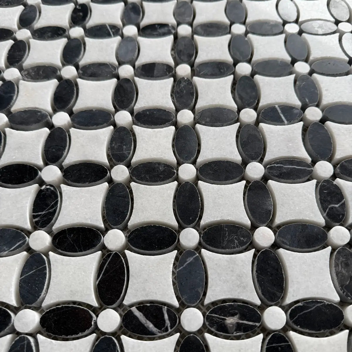 Black and white marble flower mosaic laid as a bathroom floor with white sanitaryware