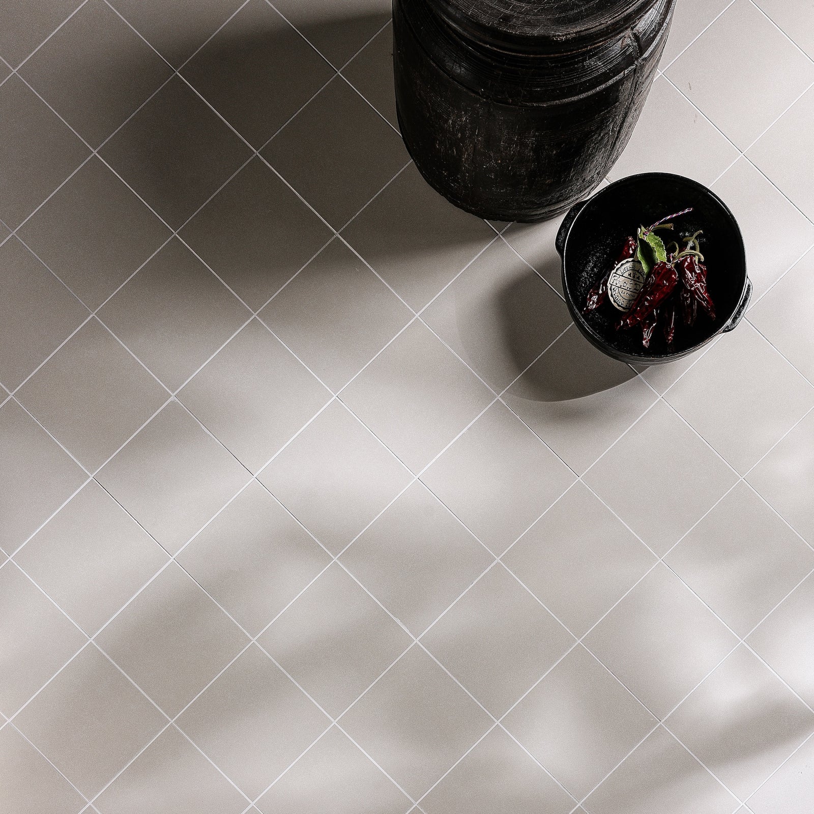 White square porcelain tiles with subtle gray undertones arranged in a diagonal grid pattern from adventuras ecru field
