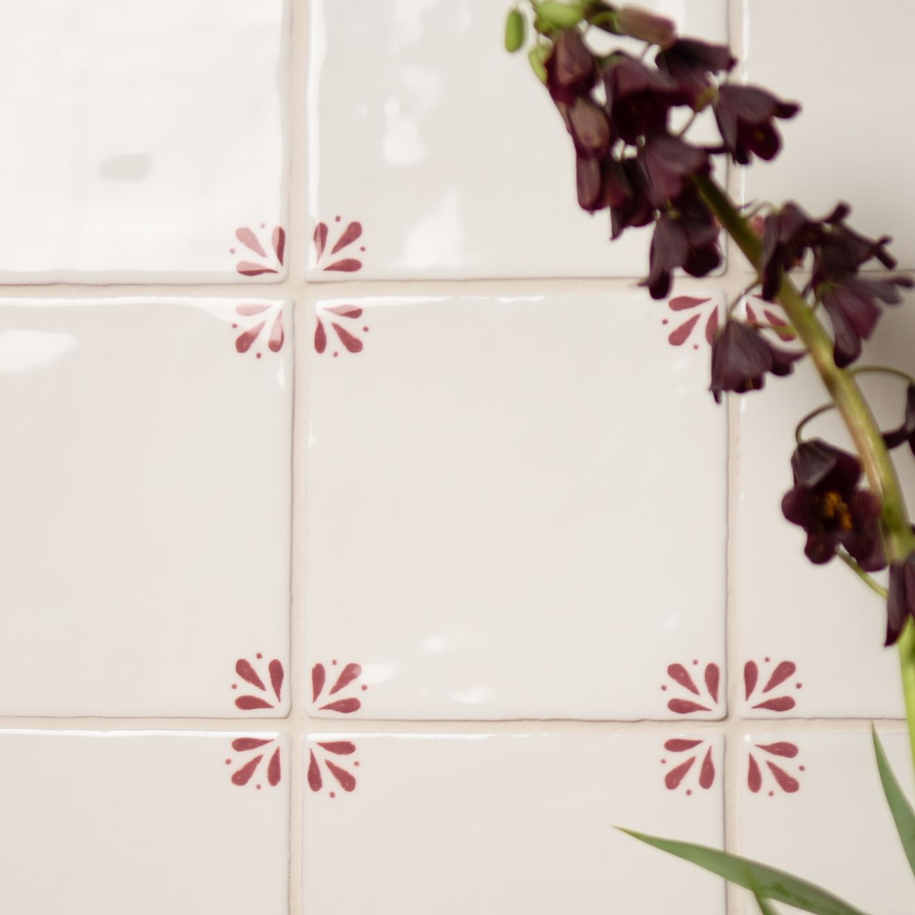 White tiles with pink floral designs and a dark purple flower against a white background