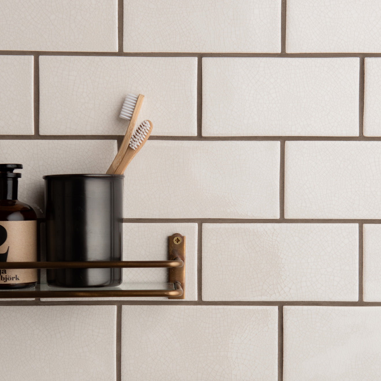 Black ceramic toothbrush holder with matte finish holding two wooden-handled toothbrushes from crackle glazed brick tile helmingham product