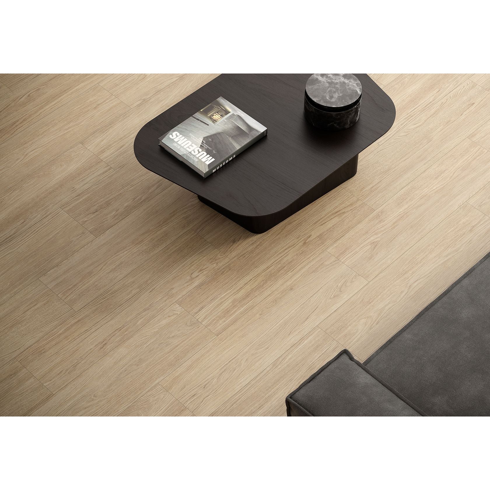 Black coffee table with a magazine and decorative item on a wooden floor in Minoli Bowland Oak Wood Effect Porcelain Tile (22.5x90cm)