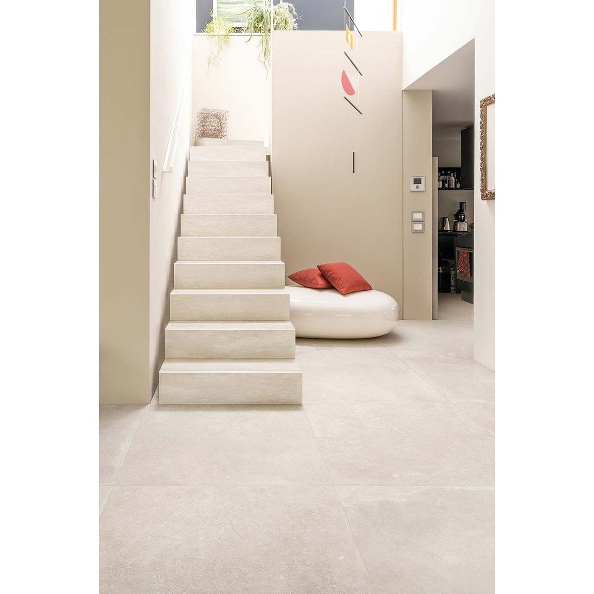 Modern interior with a staircase and a round white seat with red cushions.