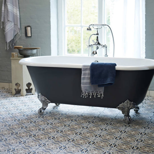 Black clawfoot bathtub with white interior and chrome fixtures showcased on abbey fountains patterned tile floor