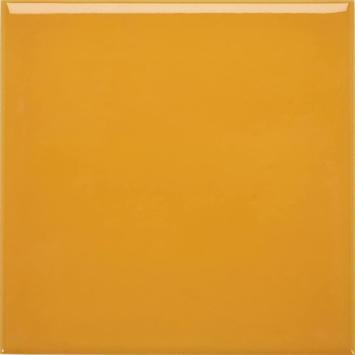 A glossy mustard yellow Acapulco Yellow City 10x10cm ceramic tile with smooth surface and slightly raised edges