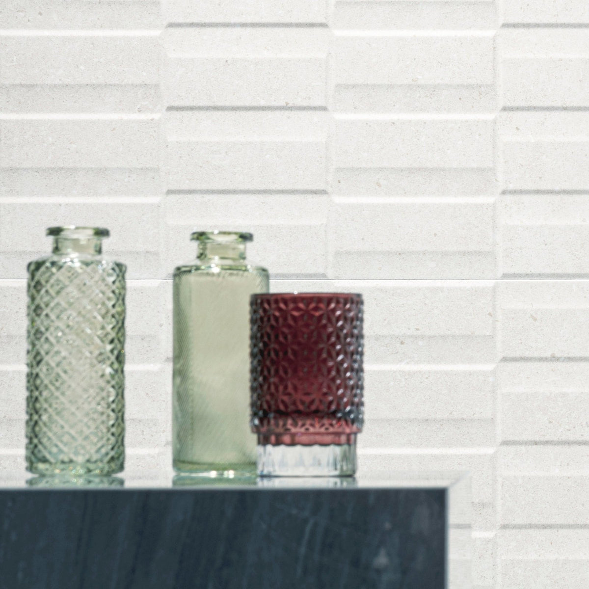 Three glass vases in clear green, pale green, and deep burgundy with textured faceted surfaces for decor use