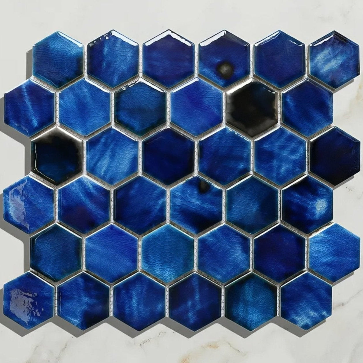 Hexagonal blue Akazu porcelain cobalt mosaic tile with glossy iridescent finish and metallic grout detailing