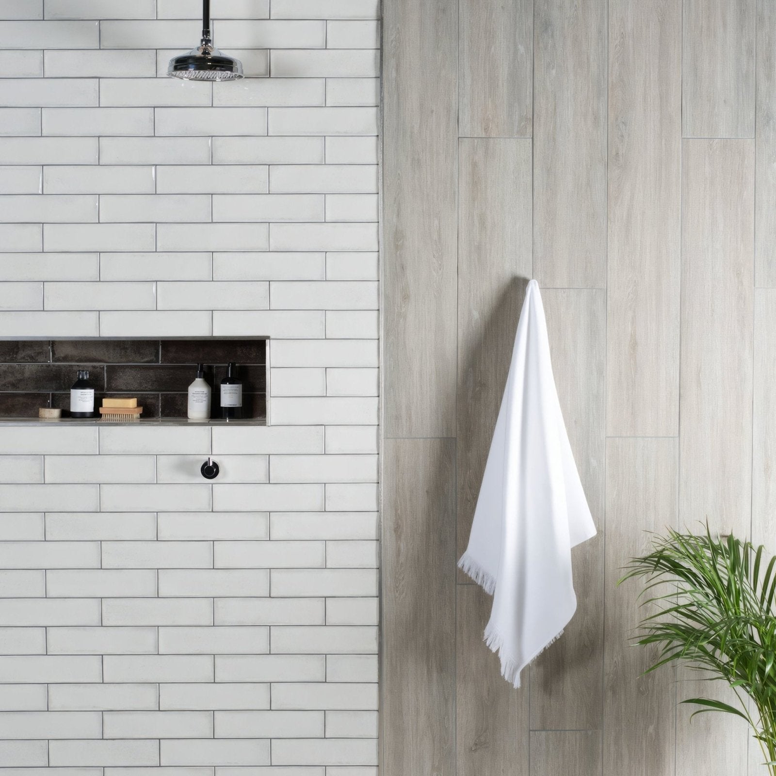A crisp white towel with soft fringed edge hanging against wall on alamo ash rectified glazed matt porcelain tile