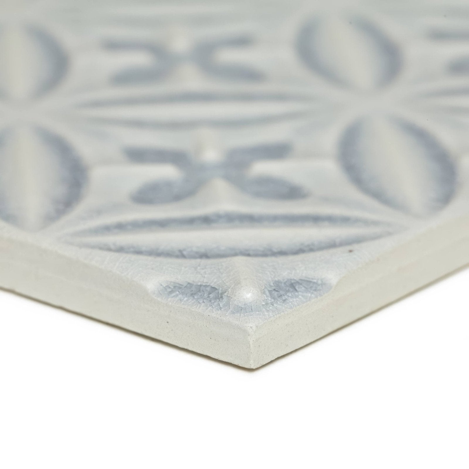 A light gray ceramic Alhambra blue decor glazed tile with a raised intricate geometric pattern