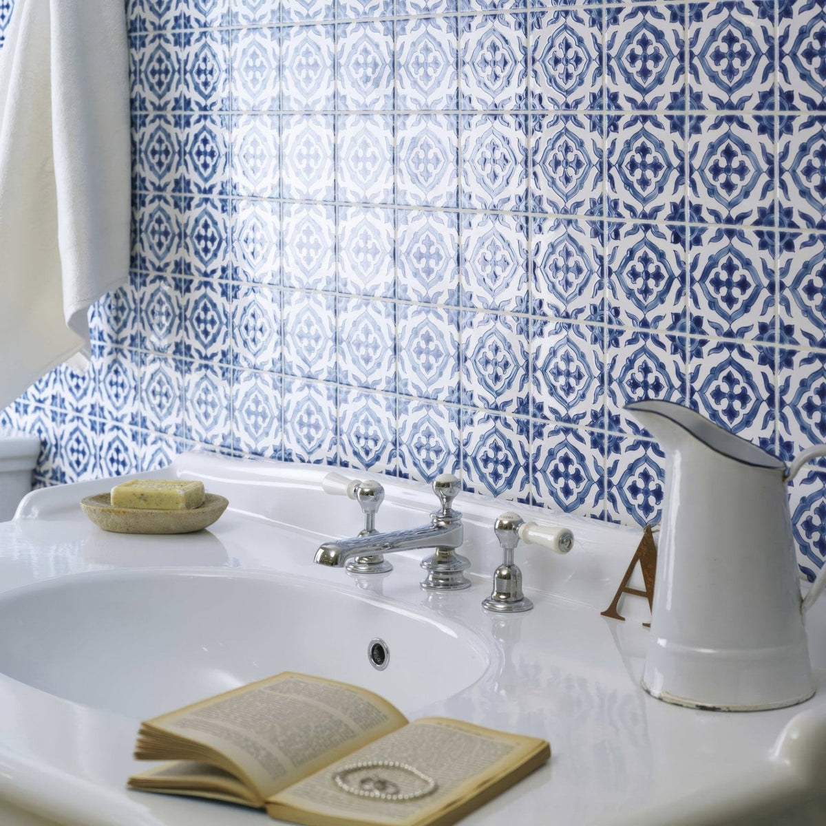 White ceramic sink with chrome faucet and white handles against blue and white andalucia jerez patterned tile backdrop