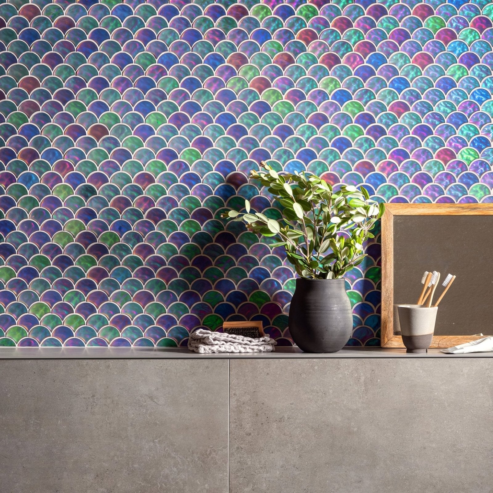 Aqua Scale Frosted iridescent fish-scale glass mosaic styled with a dark grey ceramic vase and green foliage