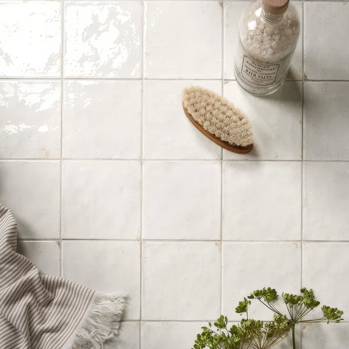 A natural-bristle bath brush with a smooth light brown wooden handle on arte italiano blanco porcelain tiles