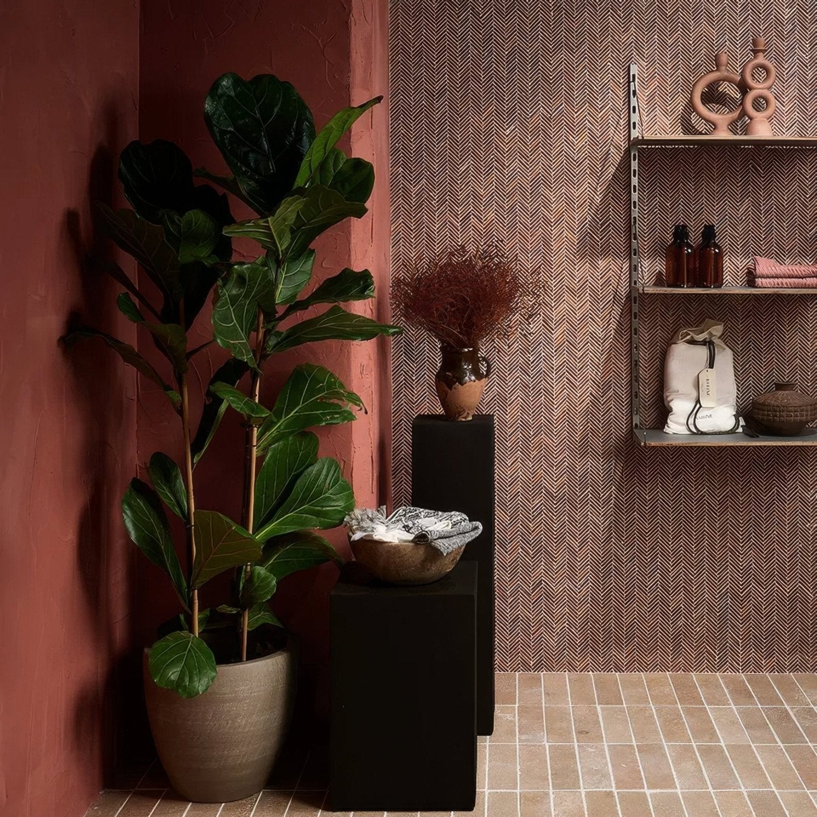 A tall fiddle leaf fig plant in a matte gray ceramic pot displayed on an Athens Rosso travertine mosaic surface