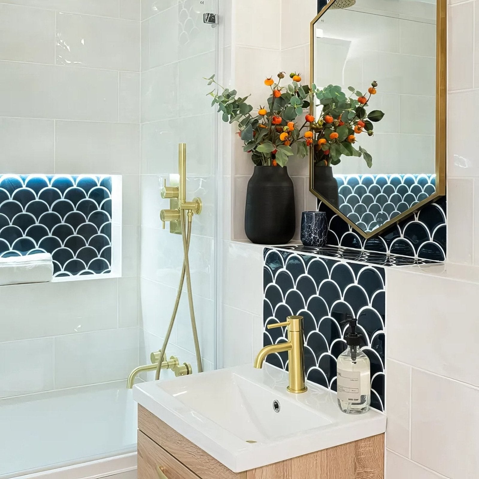 Black ceramic vase holding orange and green foliage complementing the Atlantis porcelain mosaic navy design