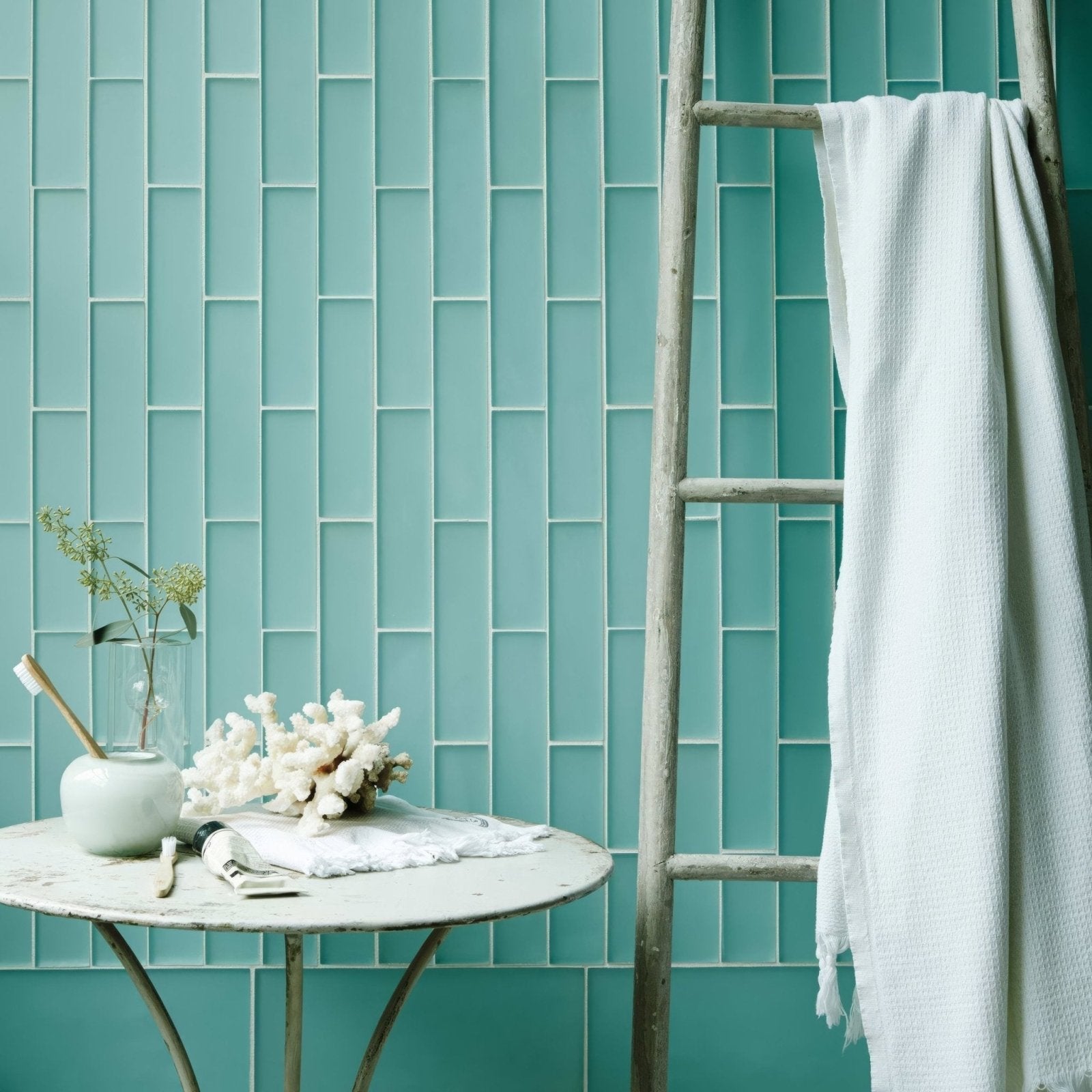 Aurora Salla Brick Glass Mosaic light blue glass brick mosaic with a towel on a wooden ladder beside it