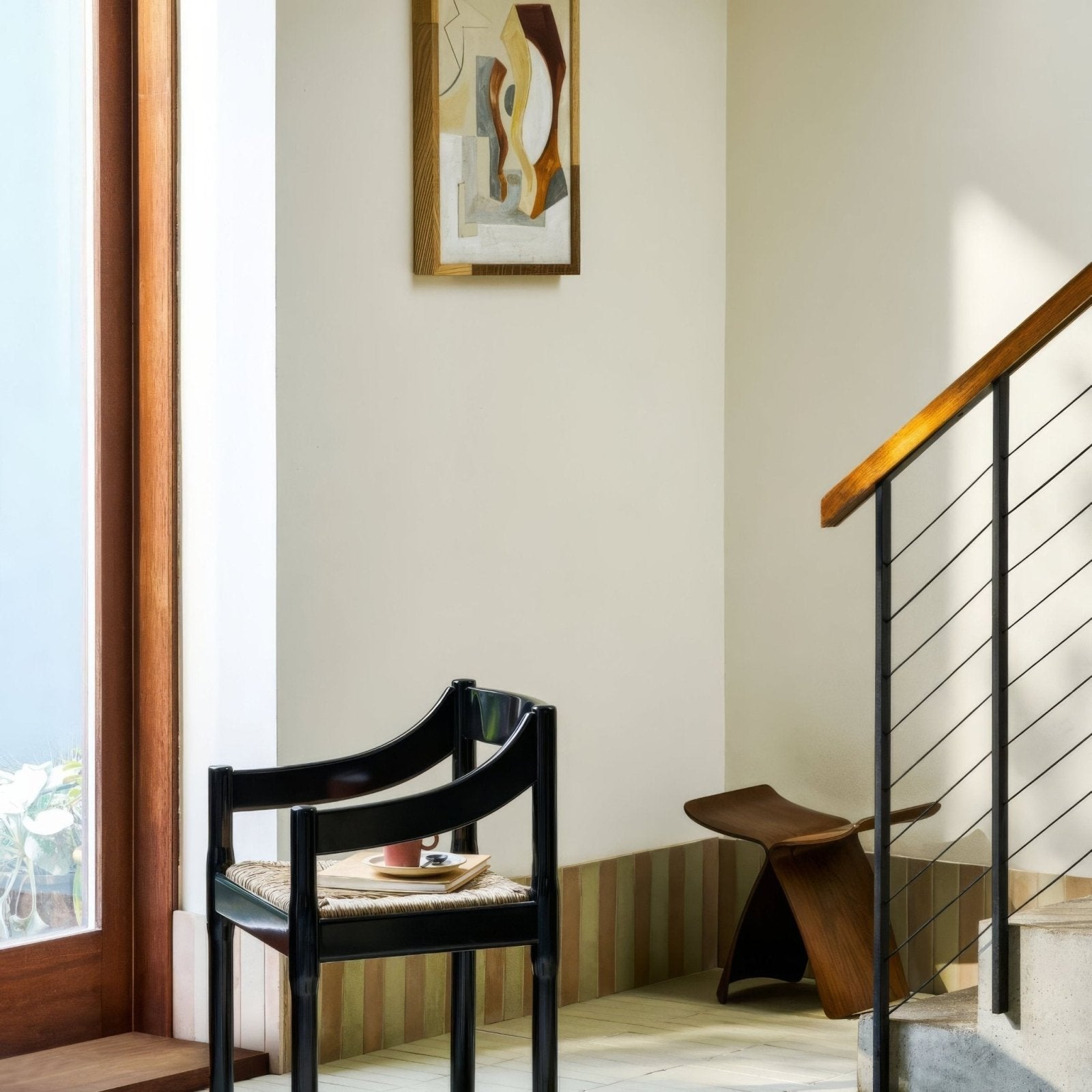 Black wooden chair with woven seat and curved backrest shown from the back in balance olive tile setting