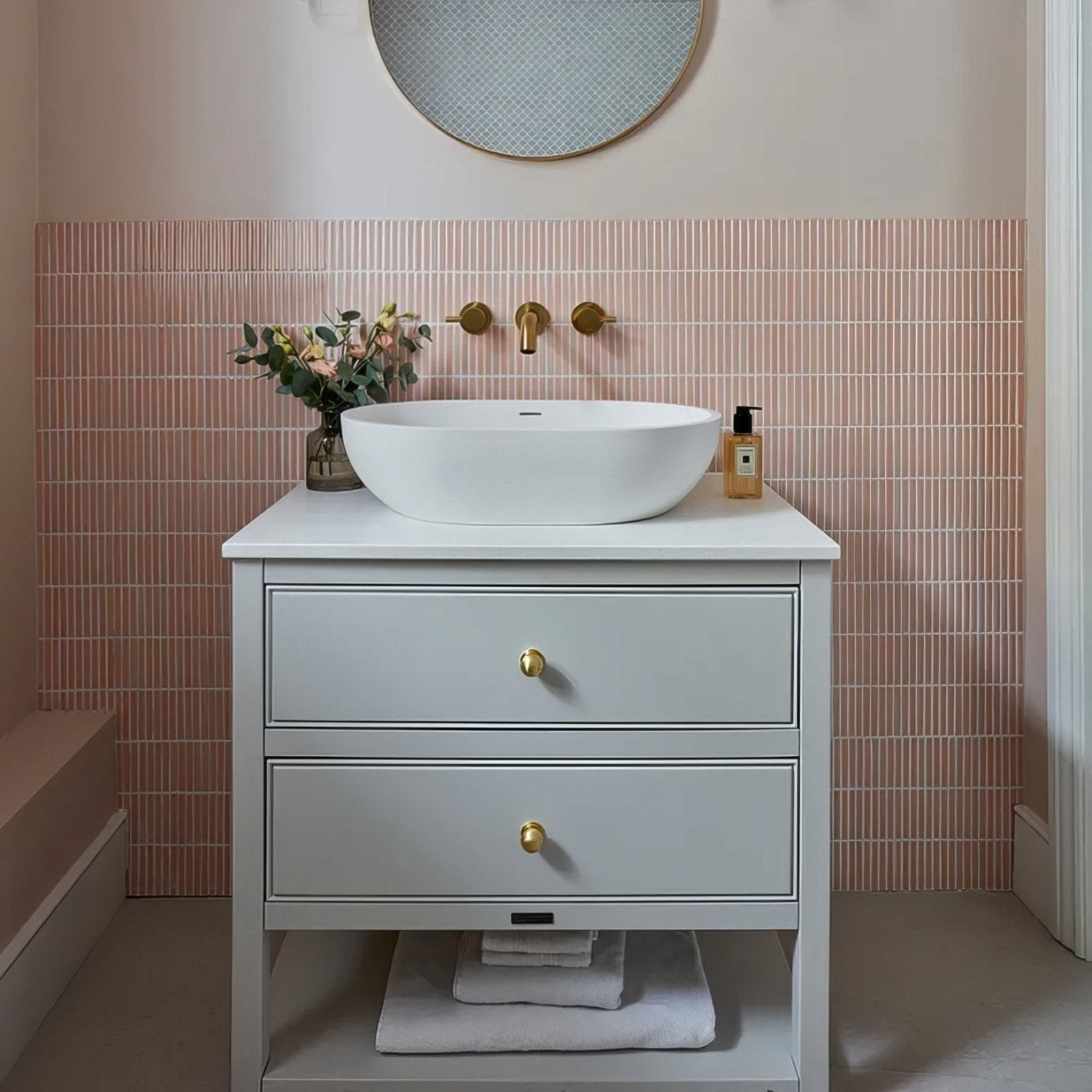 Bathroom vanity with white sink, drawers, and decorative elements against a pink tiled wall in Bamboo Porcelain Mosaic Blush