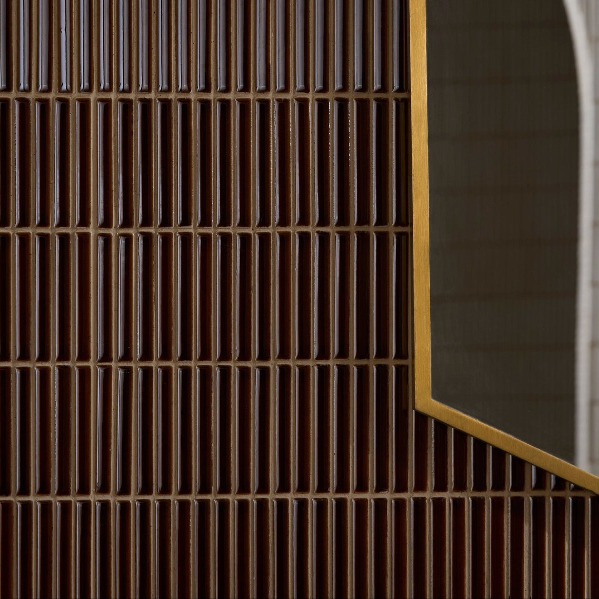 Bamboo Porcelain Mosaic Caramel dark brown ribbed porcelain mosaic beside a gold-framed mirror