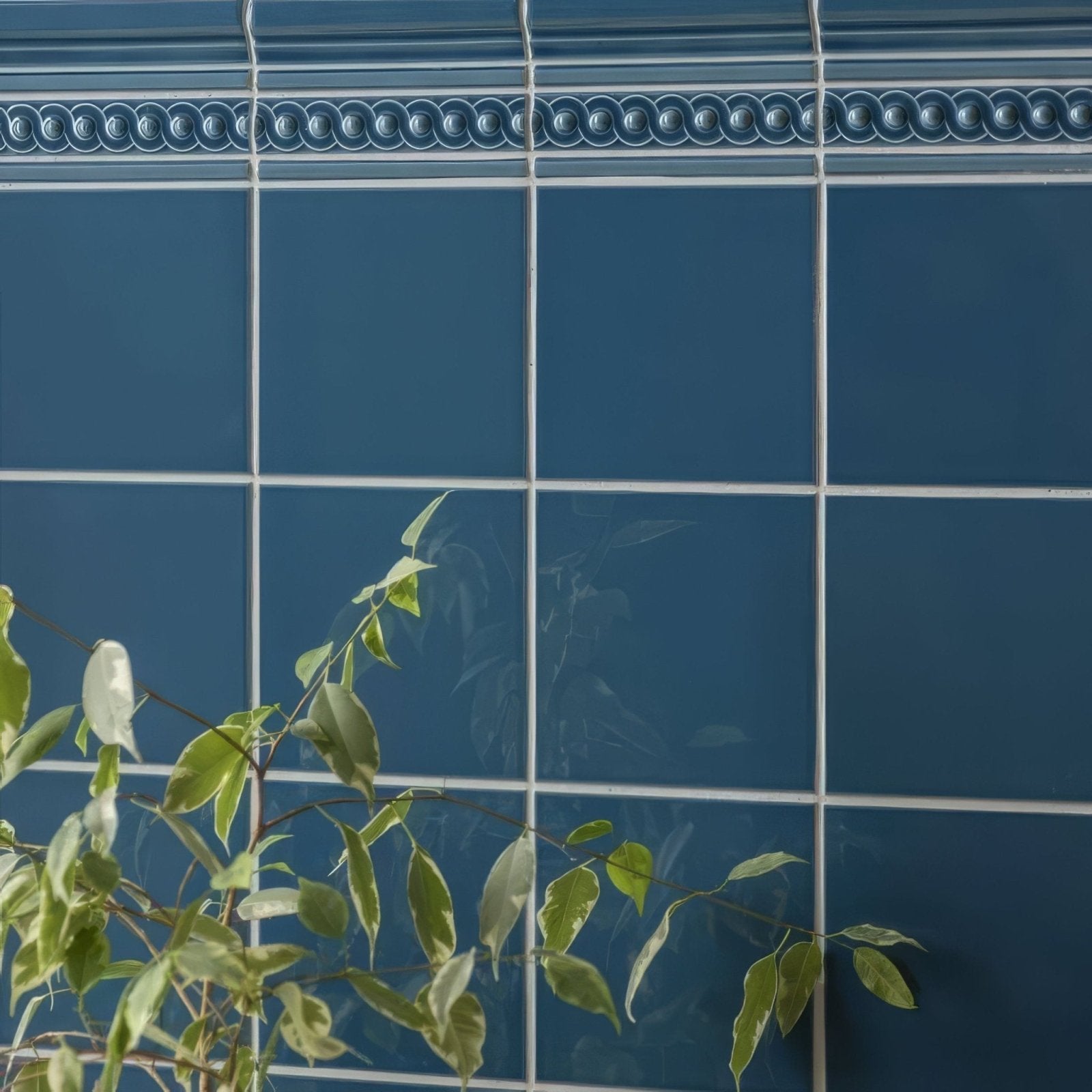 Deep blue ceramic baroque blue field tile with decorative beaded border white grout and green foliage accents