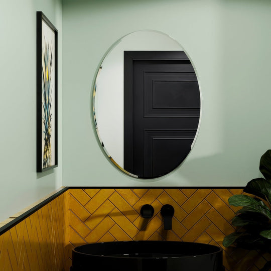 Belvoir oval mirror 55 round glass mirror with thin metallic frame mounted above black sink in bathroom setting