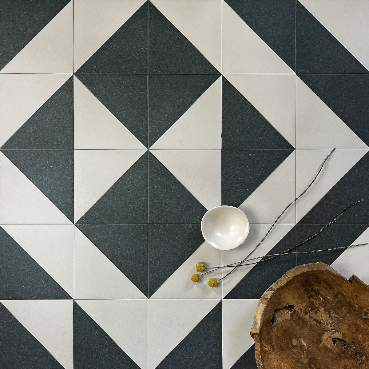 White ceramic bowl with smooth glossy finish on geometric black and white tiled surface bert and may black alalpardo porcelain