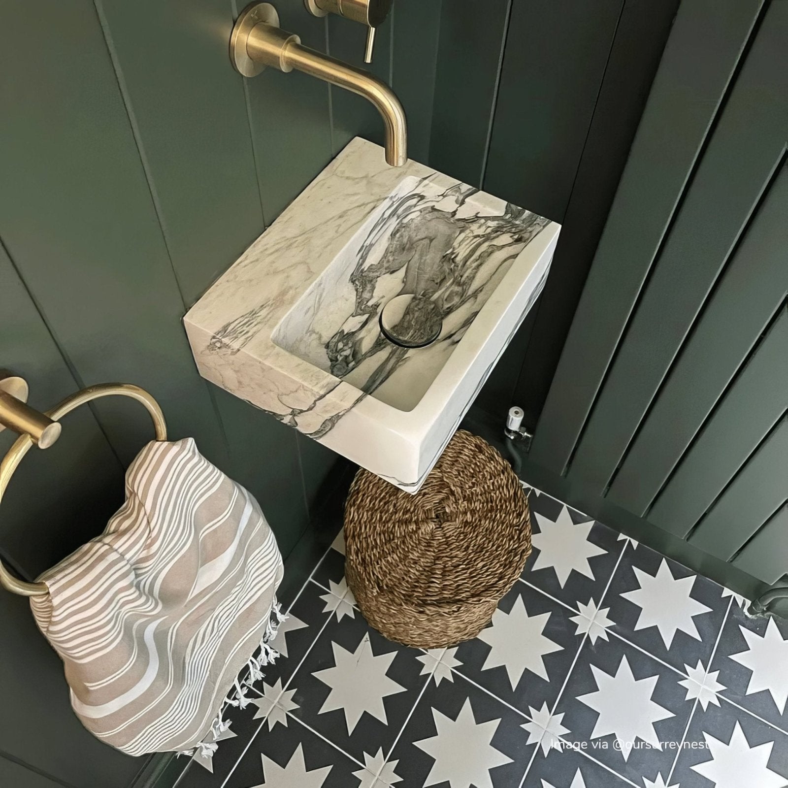 A sleek rectangular white marble sink with dark gray veining and polished brass faucet from Bert and May Black Pradena Porcelain