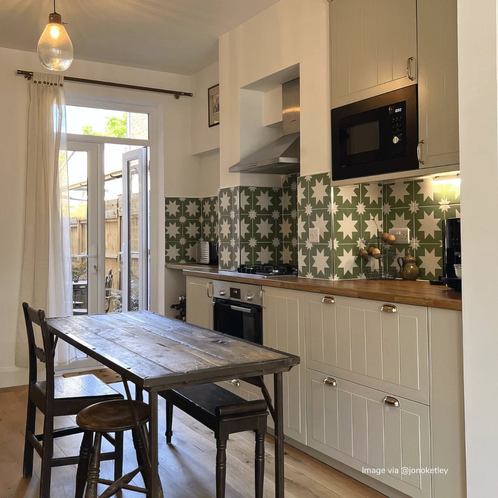 White shaker-style kitchen cabinets with silver handles and wooden countertops featuring bert and may green pradena porcelain