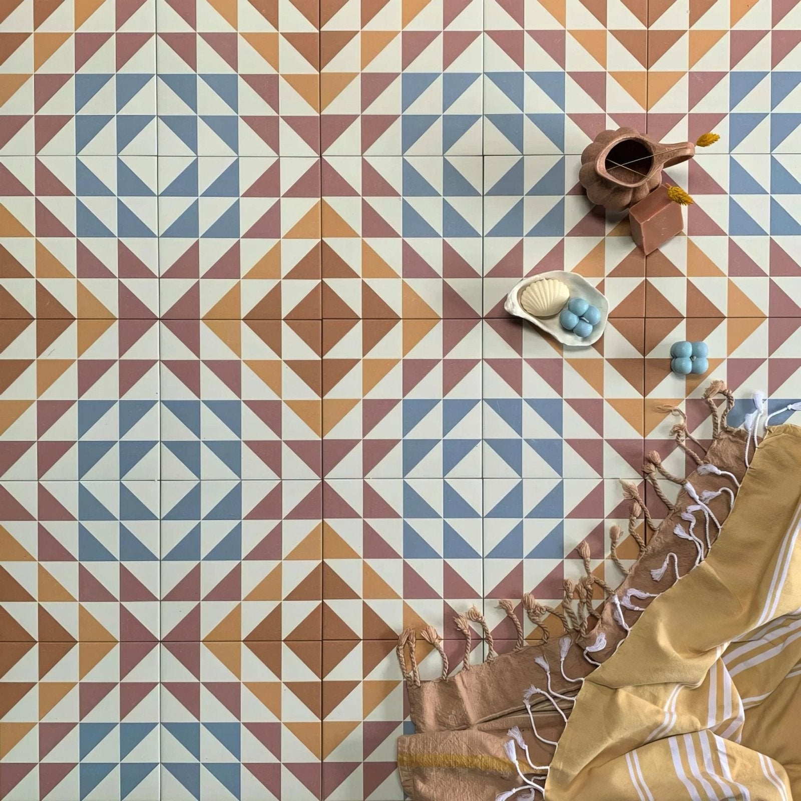 Terracotta ceramic pitcher with spout and handle resting on bert and may soho majadas porcelain tile patterned surface