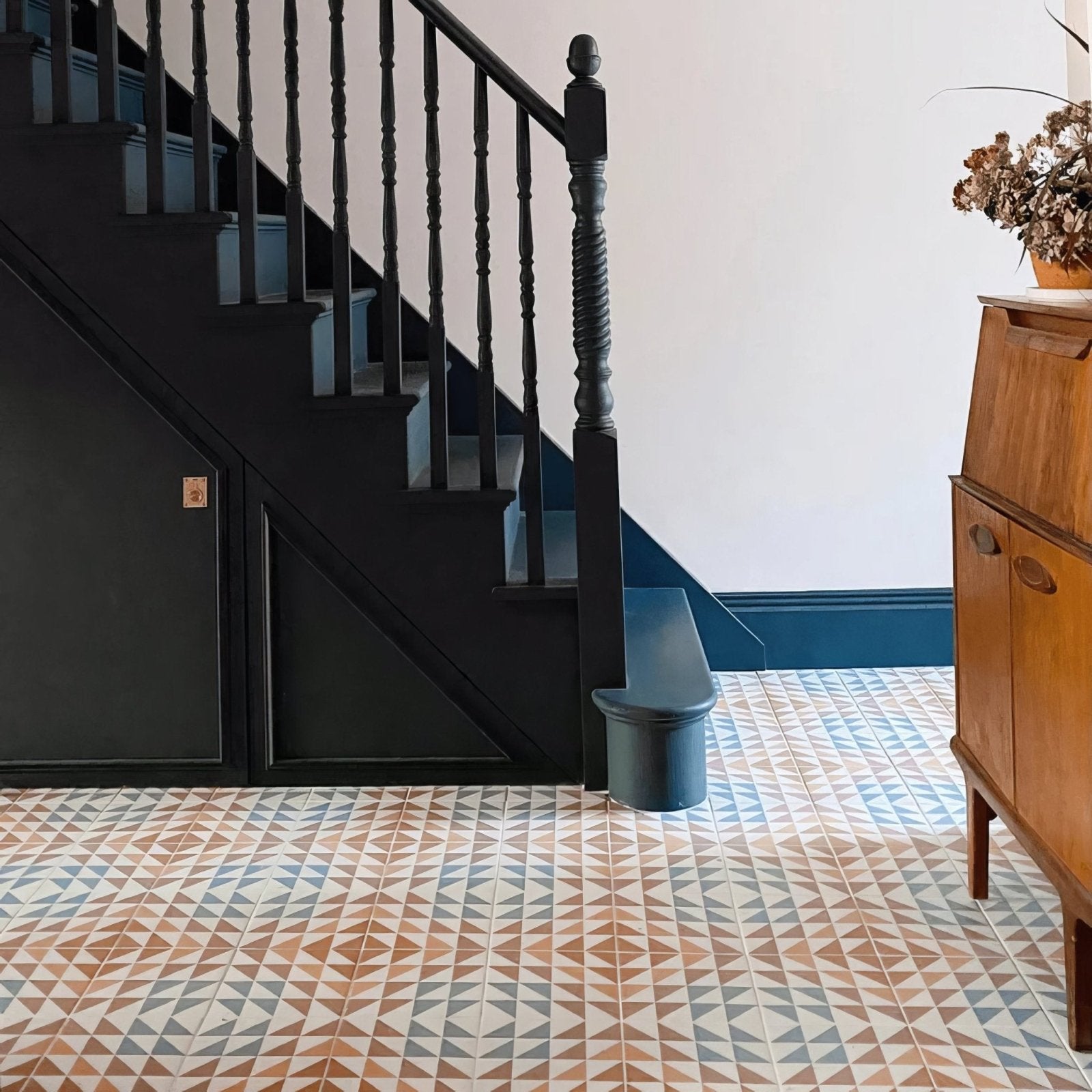 Black painted wooden staircase with ornate balusters and matching newel post in bert and may soho majadas porcelain tile setting