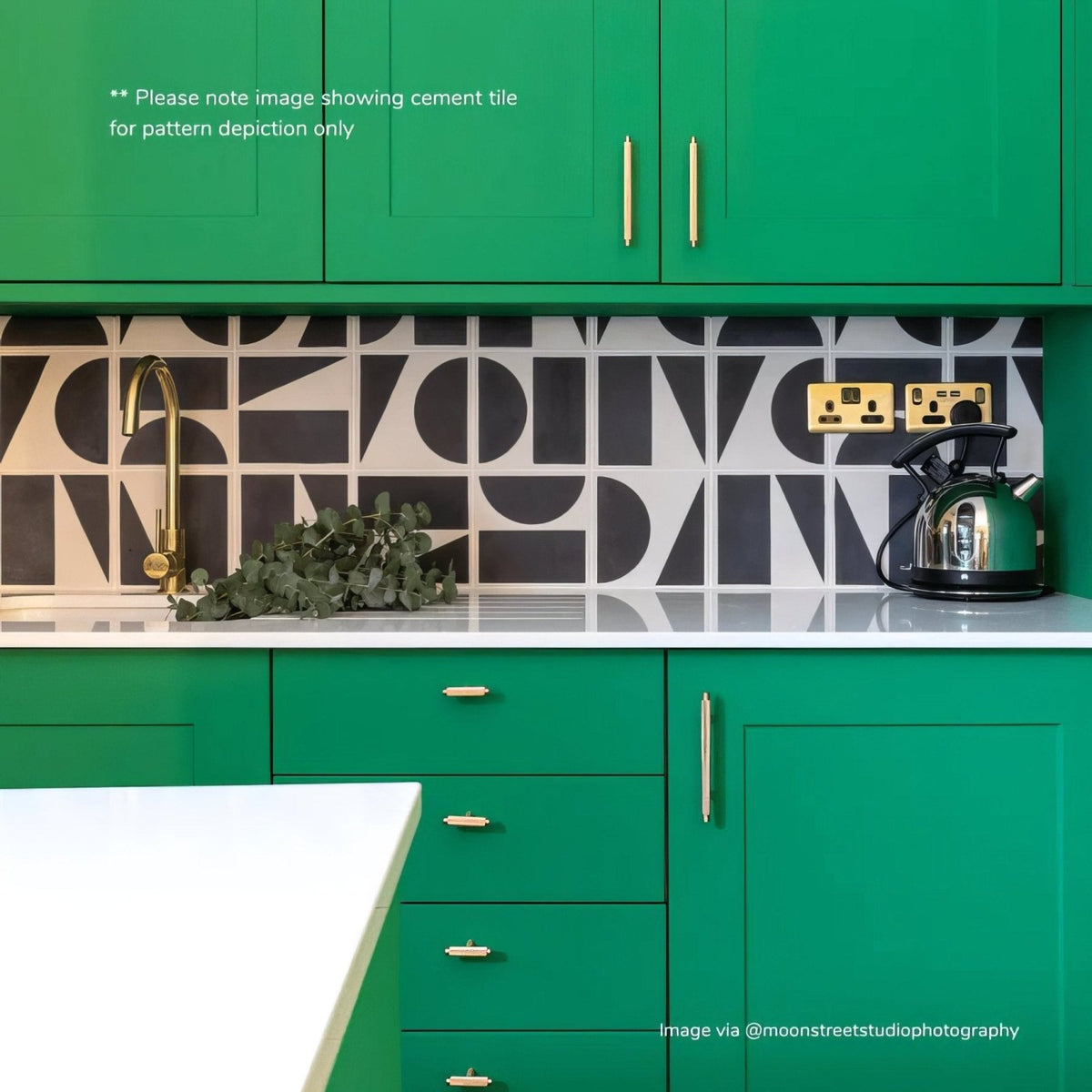Green kitchen cabinet with gold handles and geometric black and white backsplash in bert and may split shift old iron porcelain