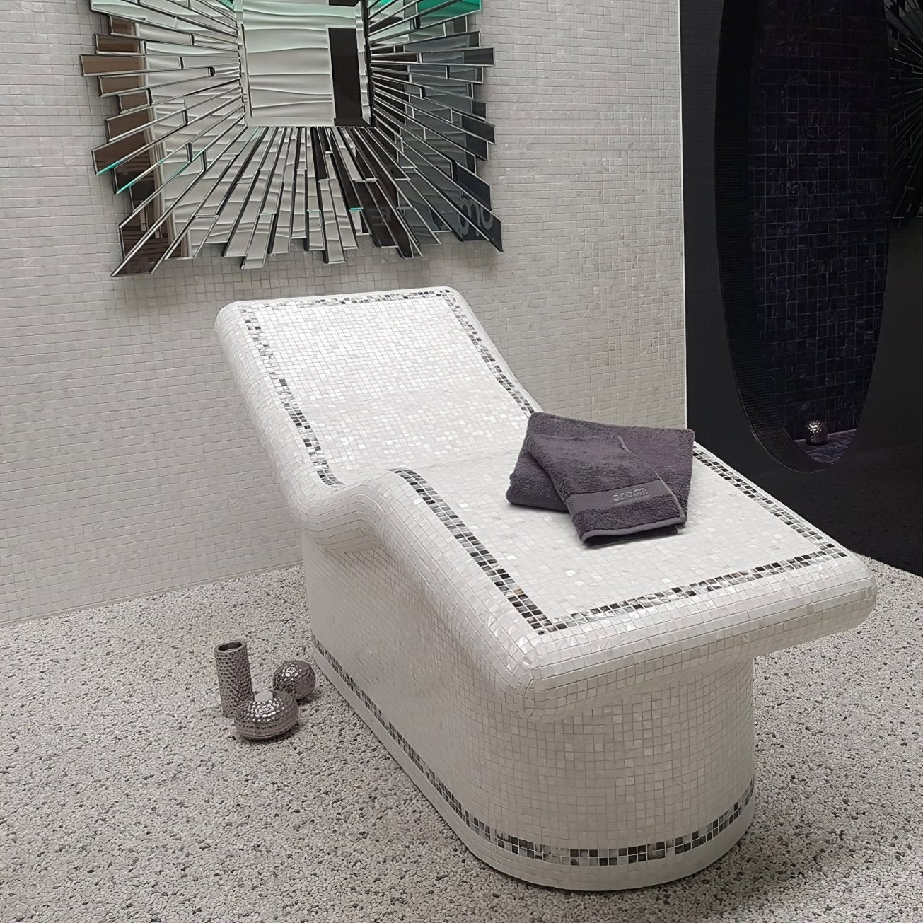 A sleek white mosaic tiled lounge chair with curved design accented by black and silver borders bianco 25mm square