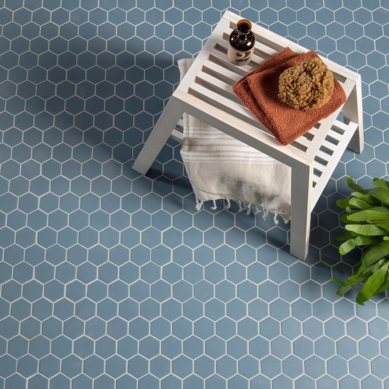White slatted wooden stool with towel and orange cloth featuring blue grey hexagon slip resistant design
