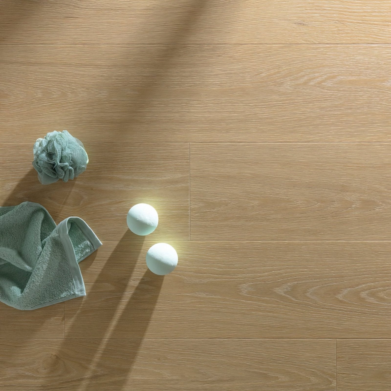 Light blue textured bath towel and two spherical bath bombs on blush f006 long vinyl planks floor