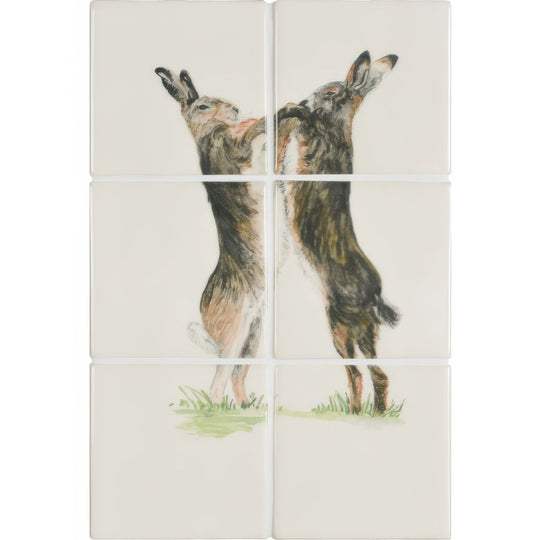Cream-colored ceramic tile panel featuring two detailed brown and gray hares in upright boxing pose on off-white background