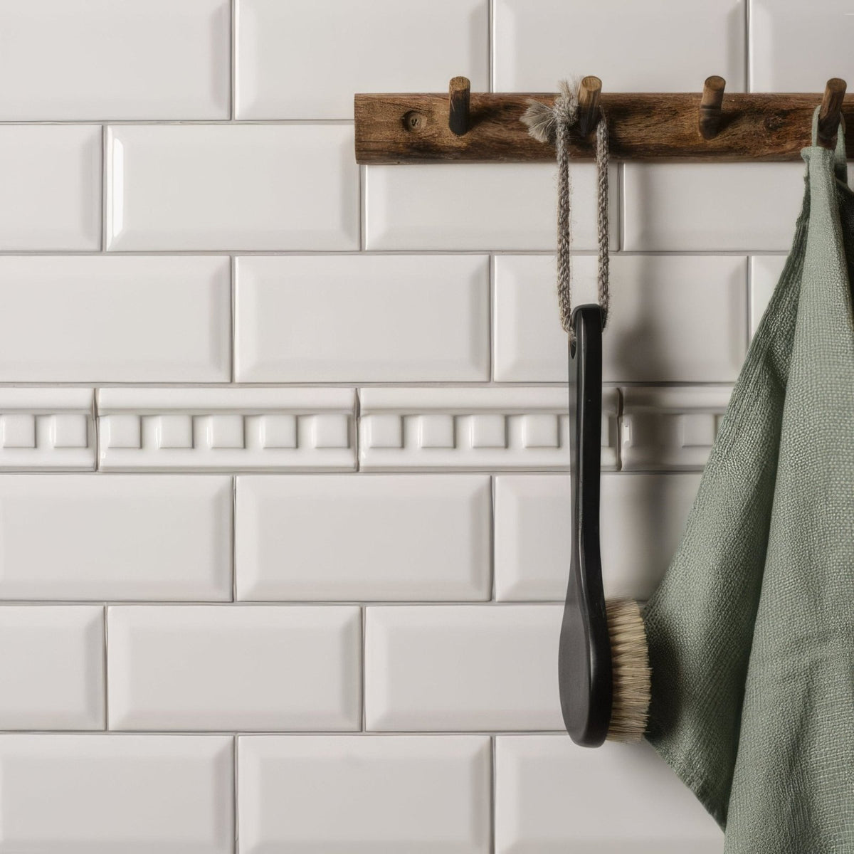 Brilliant white dentil moulding with black-handled bath brush with natural bristles hanging on wooden rack
