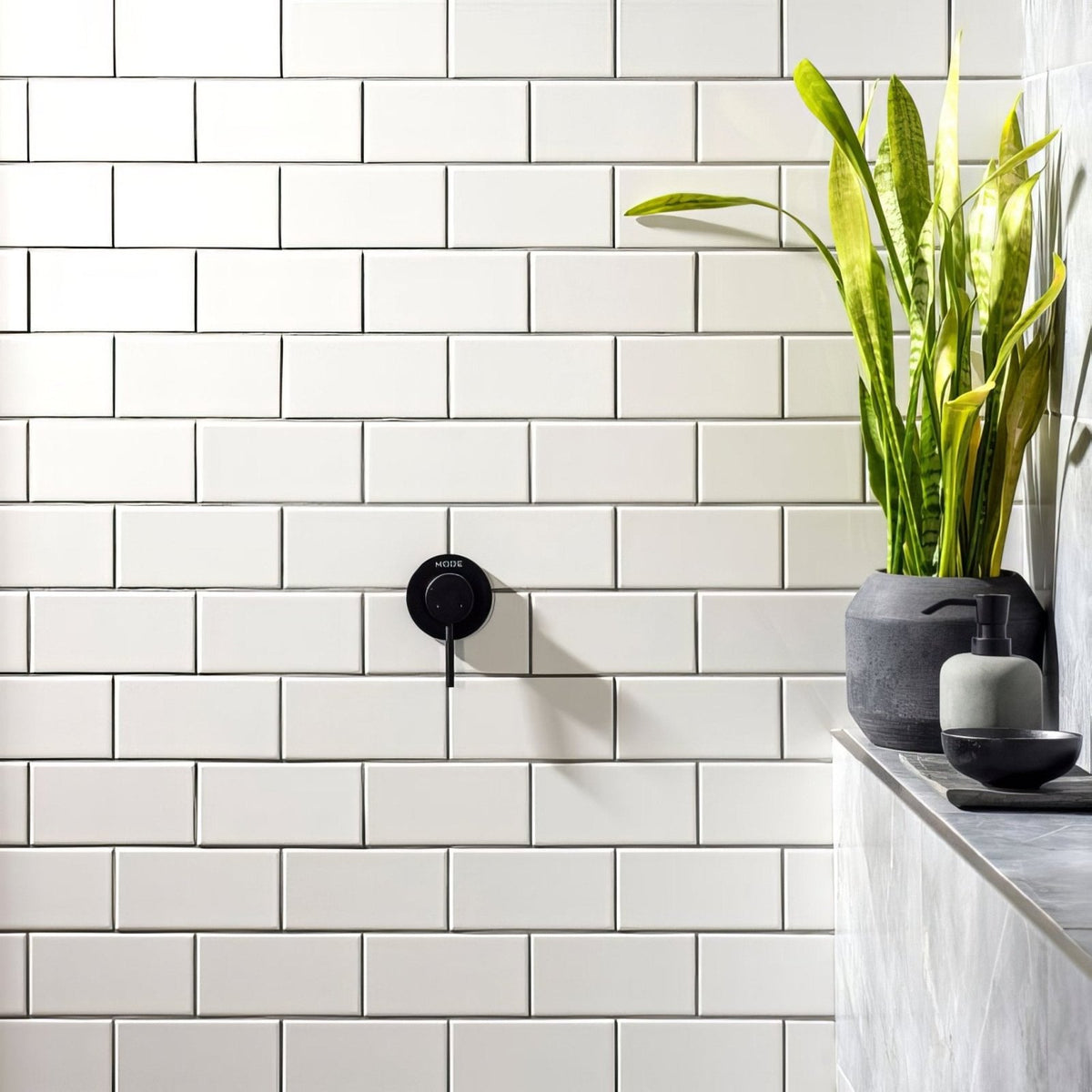 Black matte-finish wall-mounted faucet with sleek circular design and morse branding on brilliant white half tile background