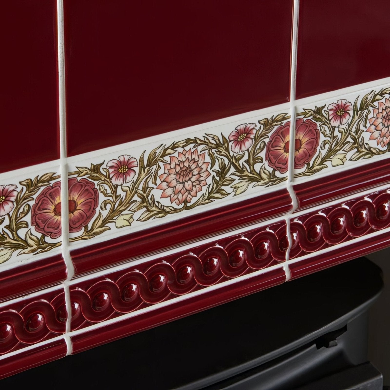 Burgundy field tile with deep red ceramic border featuring ornate pink and gold floral pattern and glossy wavy molding