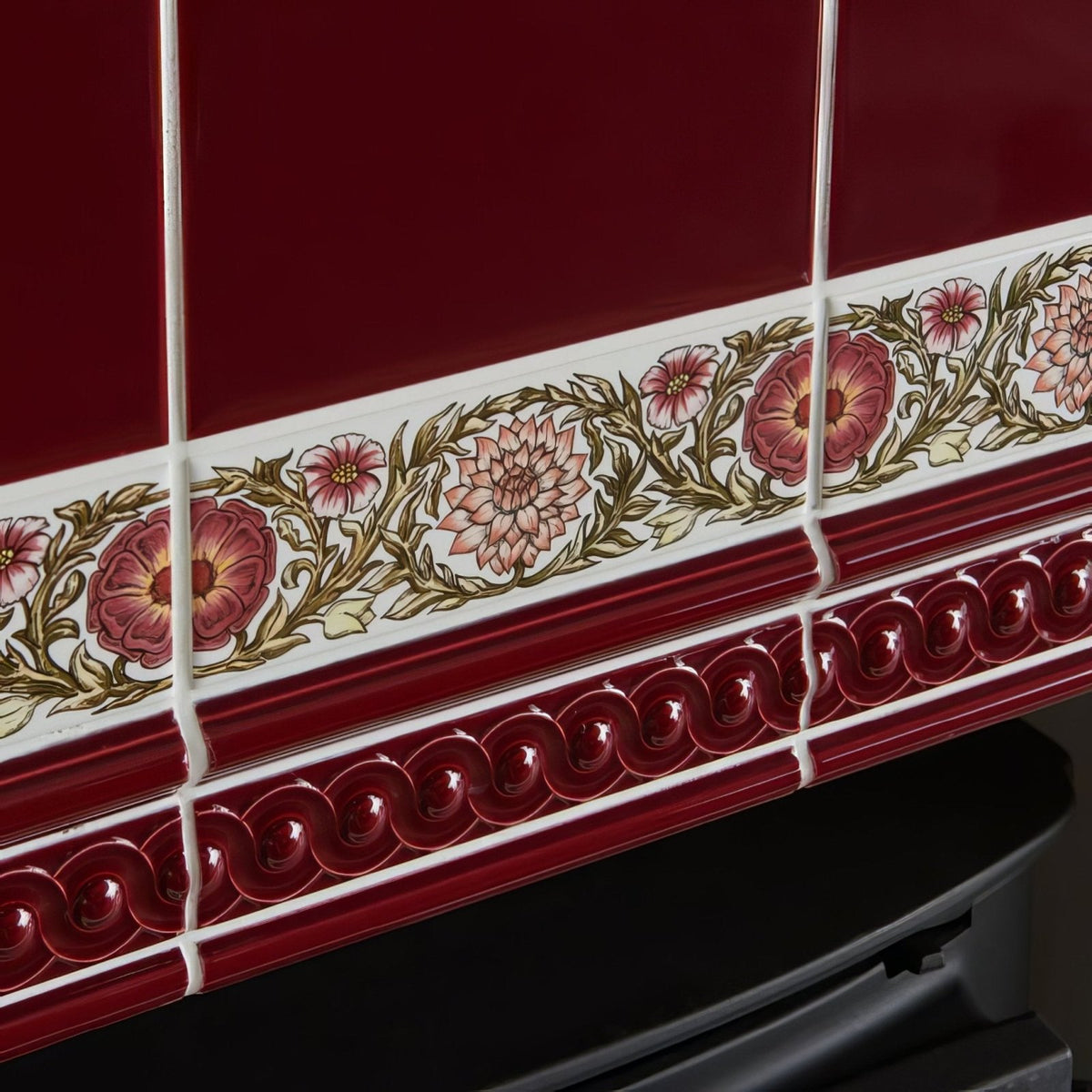 Burgundy field tile with deep red ceramic border featuring ornate pink and gold floral pattern and glossy wavy molding